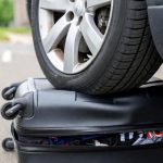 Прочный полипропиленовый корпус чемодана под колесом автомобиля - демонстрация