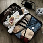 Чемодан в открытом виде с уложенными вещами - иллюстрация