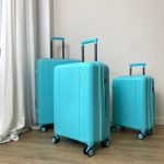 Три бирюзовых чемодана Mironpan Classic разного размера с выдвижными ручками, стоят на деревянном полу у белой стены.