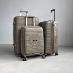 Чемодан Mybag Krug бежевый, вид спереди с поднятой выдвижной ручкой, закрытым дополнительным отделением рядом с чемоданами бежевого цвета