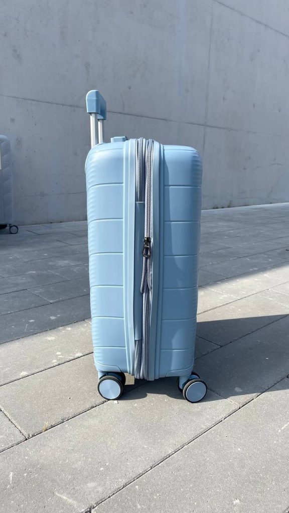 Чемодан Freedom NW голубой, вид слева с поднятой выдвижной ручкой и боковыми ножками