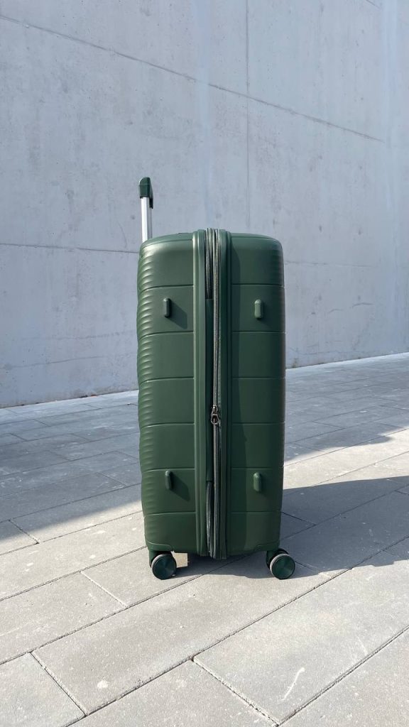 Чемодан Freedom NW зелёный, вид слева с поднятой выдвижной ручкой и боковыми ножками